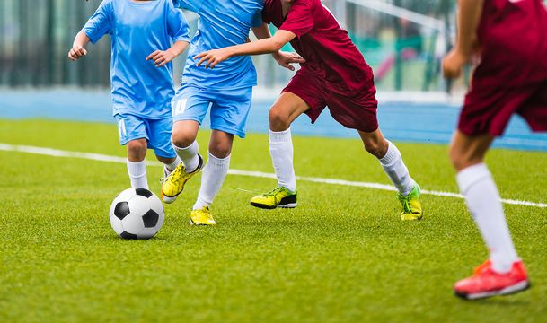 Young soccer players running towards soccer ball. Football soccer game for youth teams. Children playing soccer match